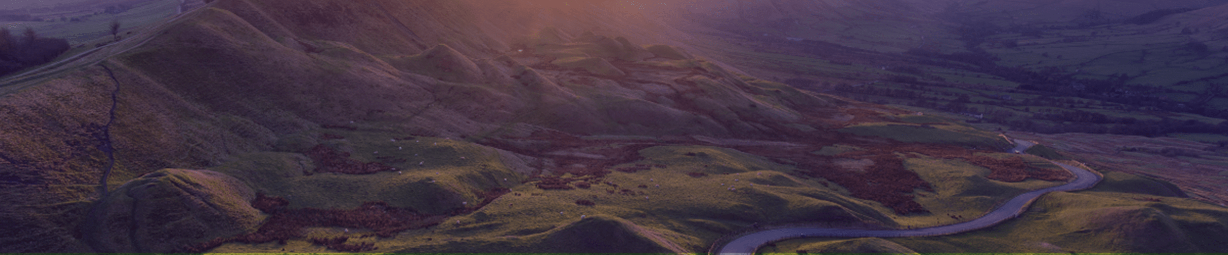 Sunset at Mam Tor in the Peak District with long winding road leading through valley